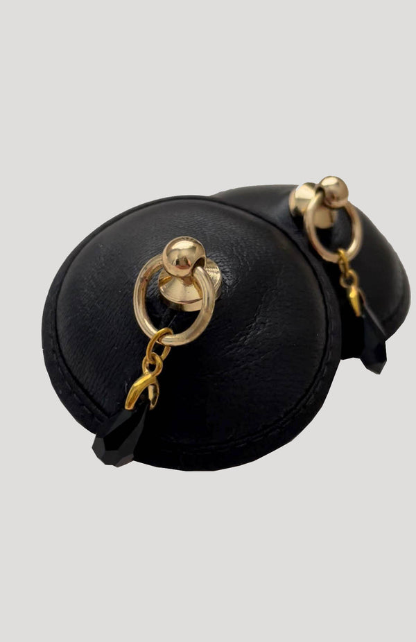 Luxury nipple pasties in black leather with gold ring and crystal pendant part of the erotic designer lingerie collection